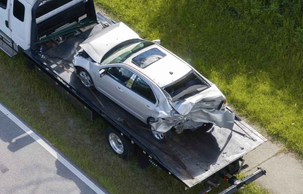 Flatbed tow truck recovering a damaged car after an accident near North Babylon, NY